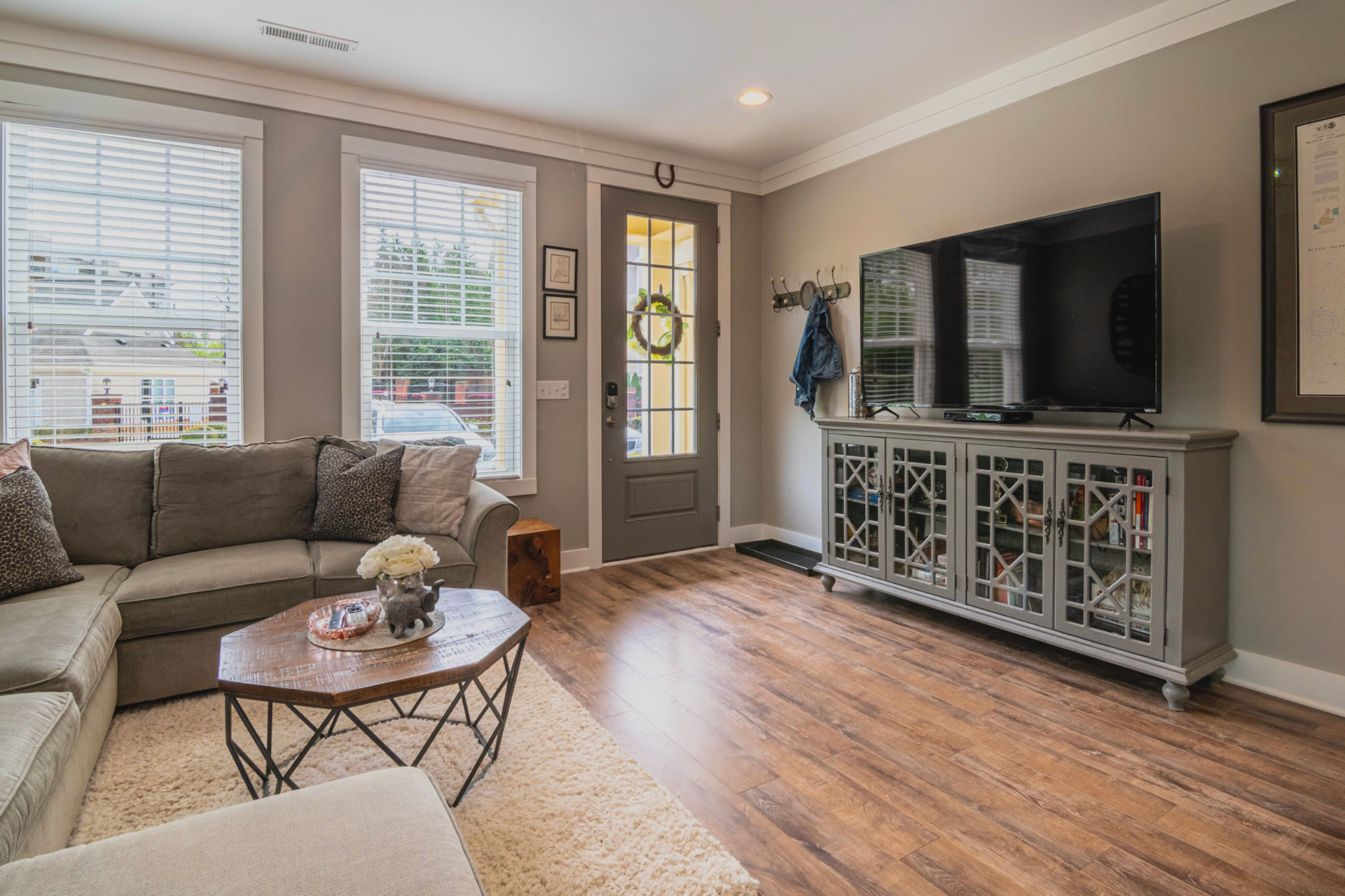 Tidy living room with a gray sectional, wood floors, and clean windows in a Cleveland west side OH home